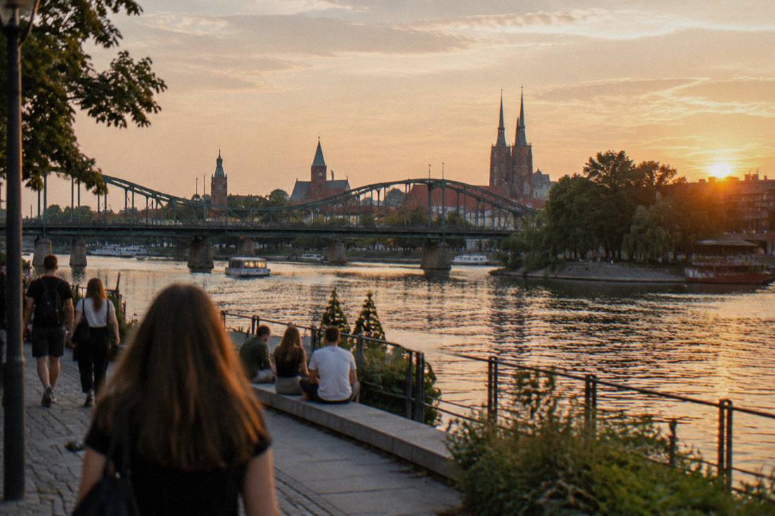 An evening view of the Odra river and Wroclaw bridges from a riverside embankment