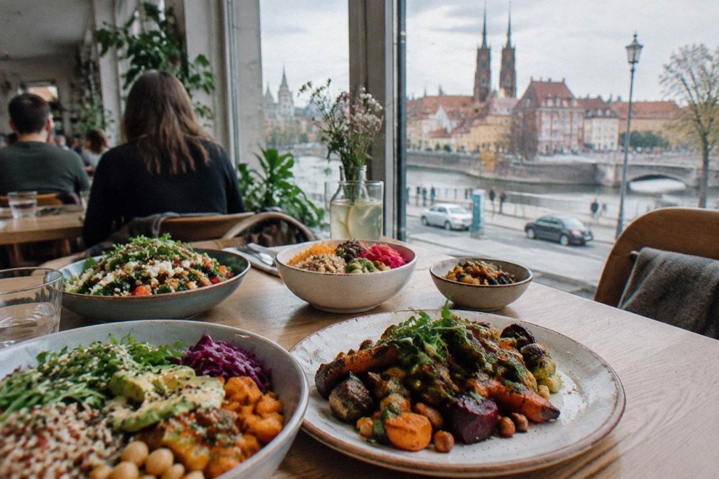 A table of colorful plant-based dishes including salads, roasted vegetables and grain bowls in a bright restaurant