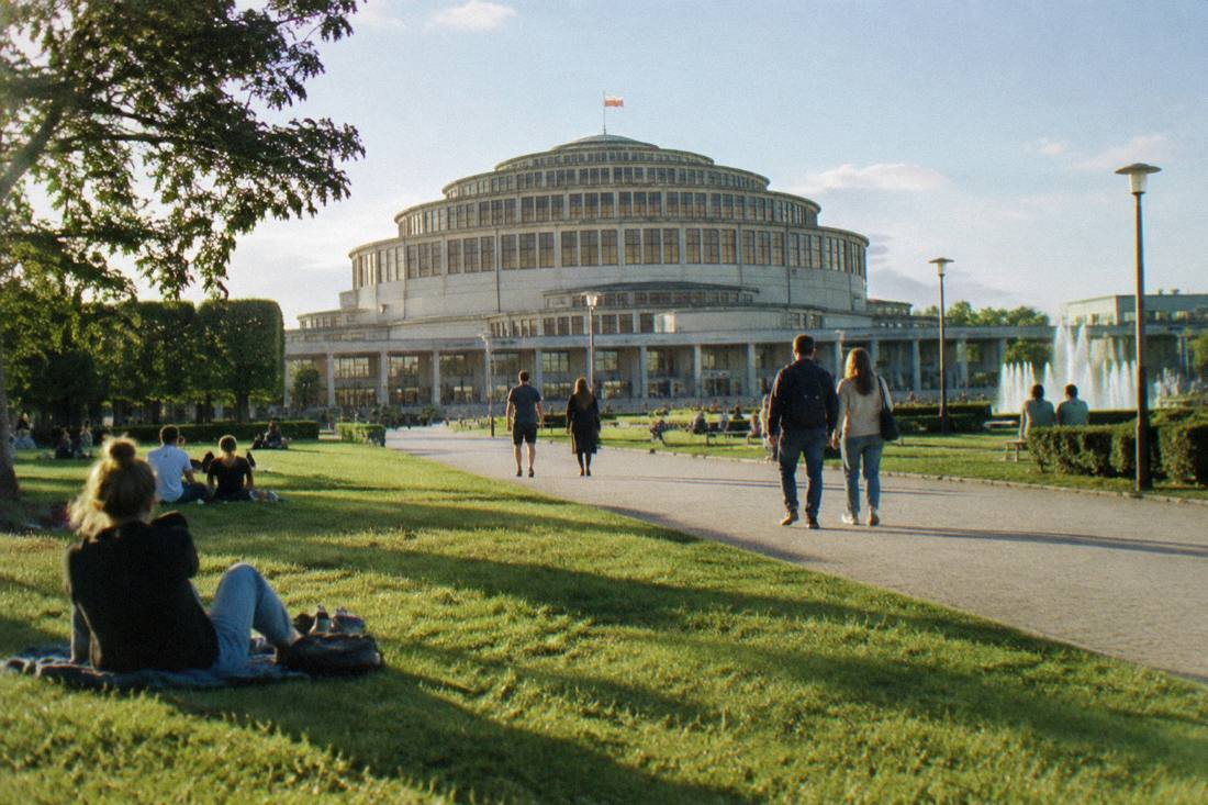People relaxing on the lawns and paved walks around Centennial Hall in Wroclaw on a sunny day