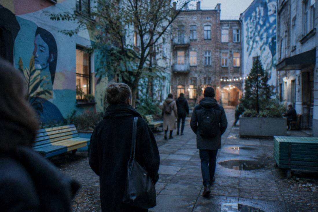 People walking through a renovated courtyard with painted walls and benches