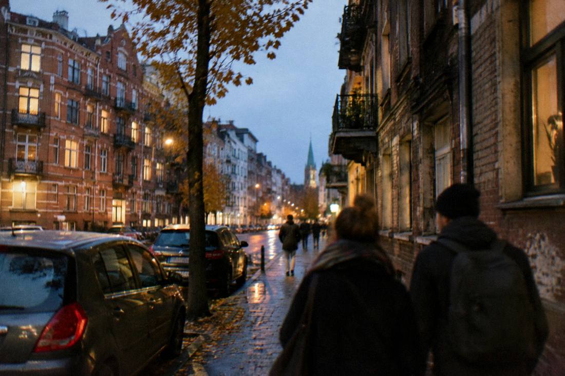 An evening street in a revitalized district with warm lights in apartment windows