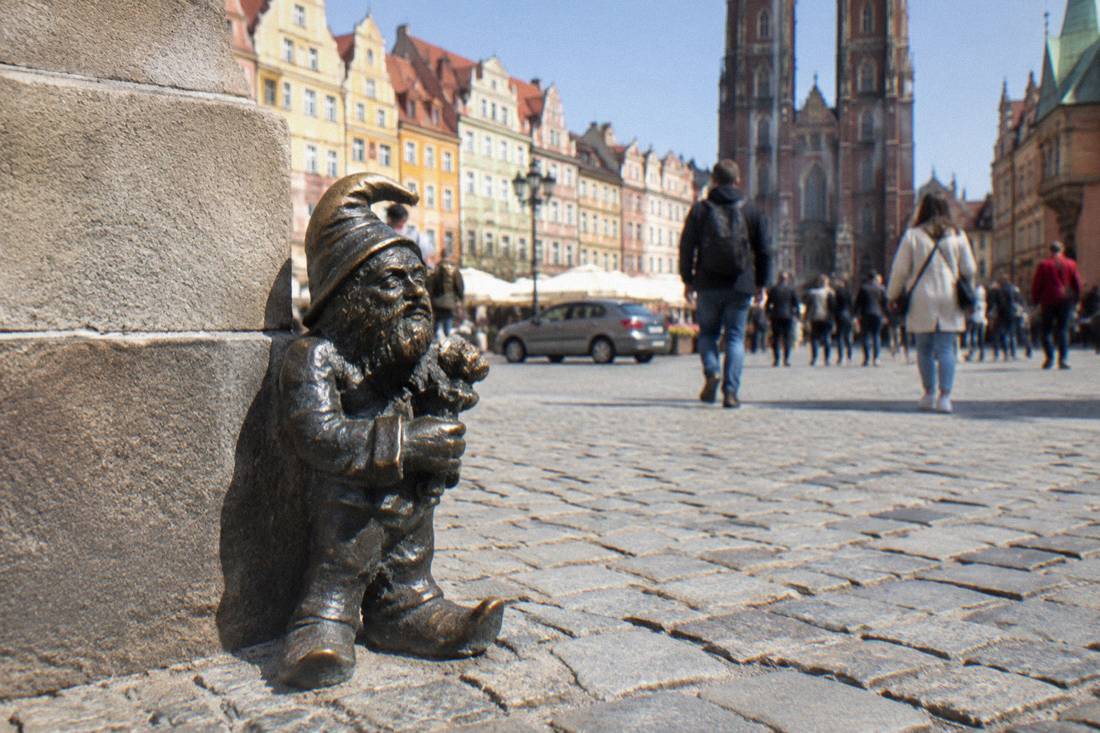 A bronze dwarf statue on a cobblestone street near the Market Square in Wroclaw