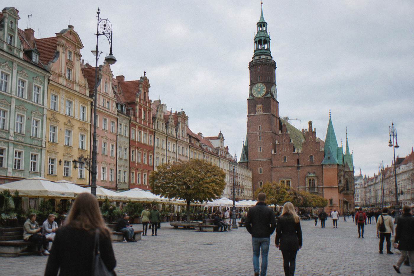 Visitors walking across the colorful painted townhouses on the Wroclaw market square in late afternoon light