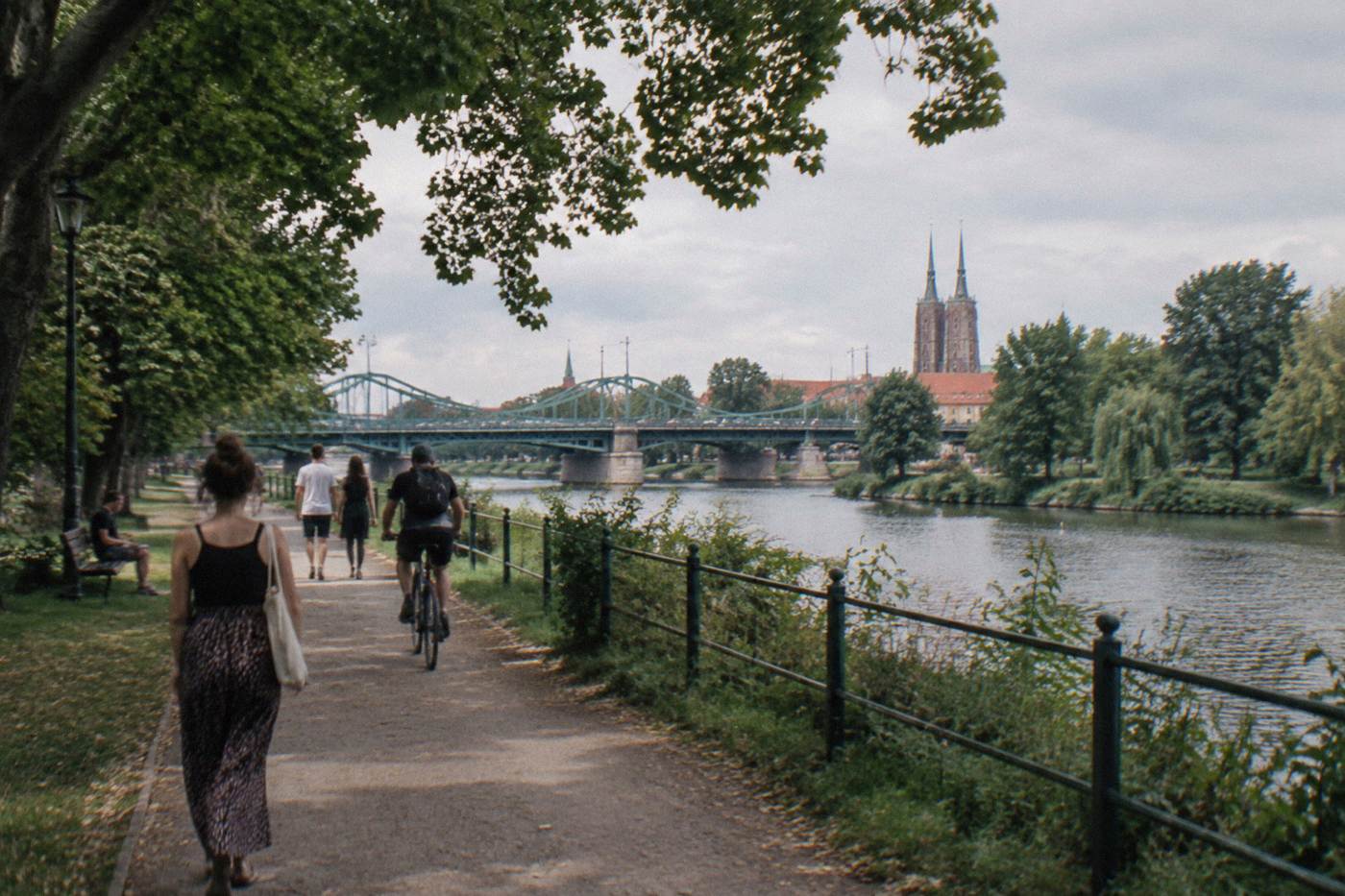 Tree-lined park path beside the Odra river in Wroclaw on a warm afternoon