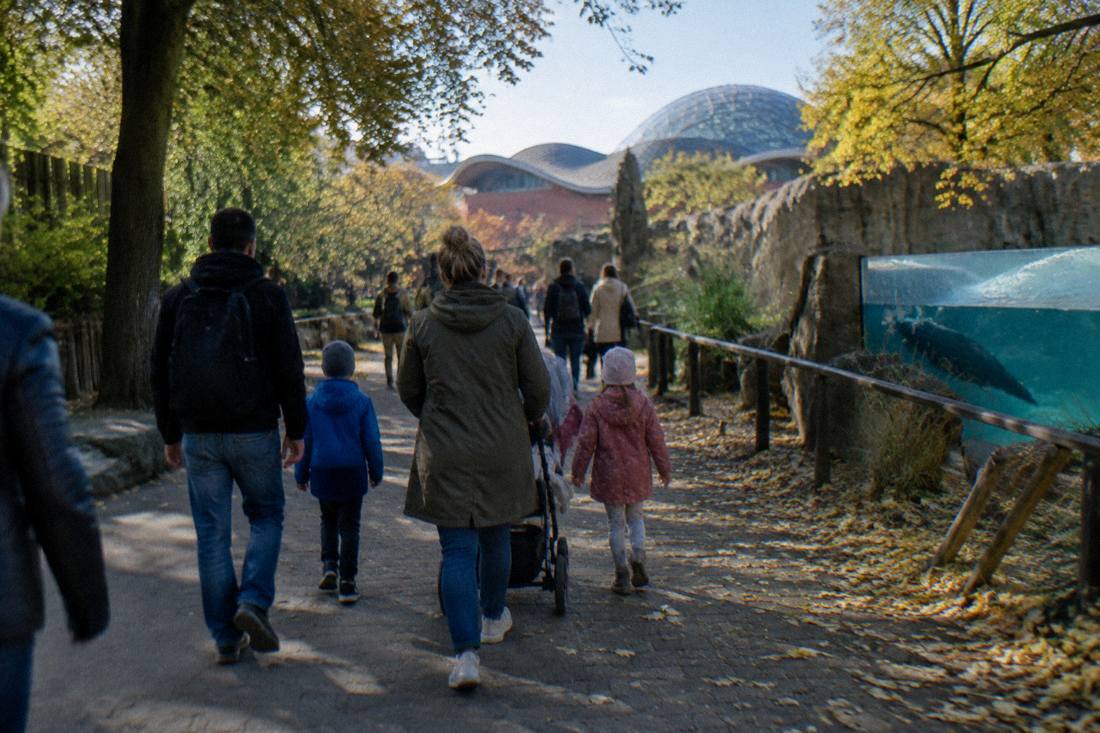 A family with children walking a shaded zoo pathway in Wroclaw