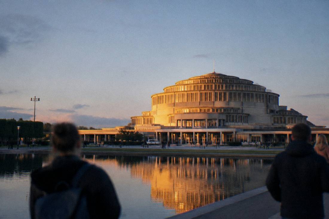 Golden evening light on a symmetrical concrete facade with a reflecting pool in front