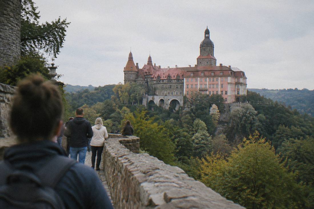 A large hilltop castle with towers above a forested valley