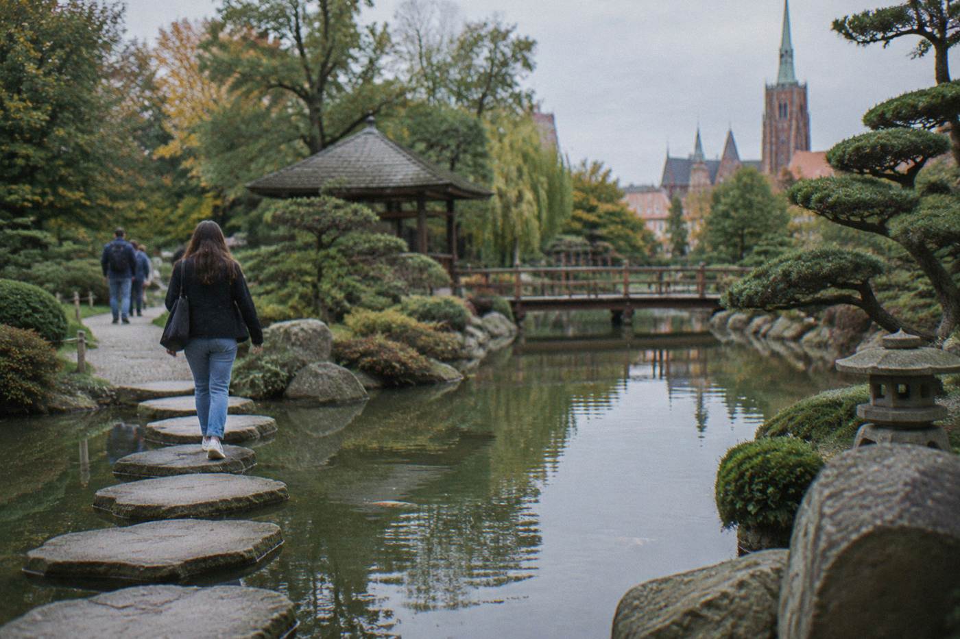 A quiet pond with stepping stones and pruned trees in the Japanese Garden in Wroclaw