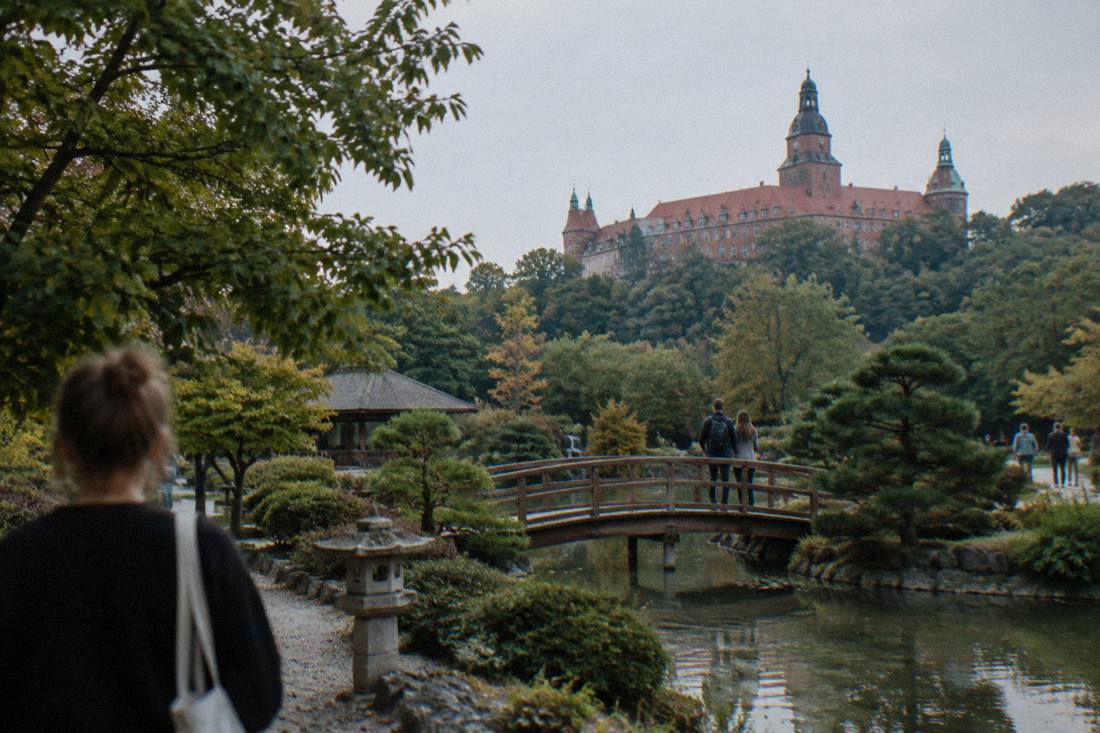 The terracotta bulk of a large Lower Silesian castle rising above forested hills