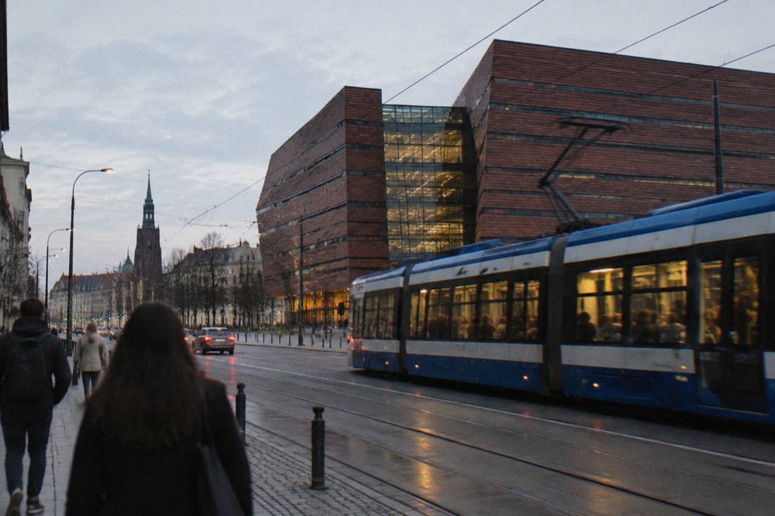 A modern tram moving along a street in central Wroclaw in the evening