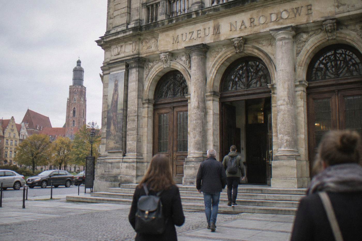 The stone facade of the National Museum in Wroclaw with visitors walking toward the entrance