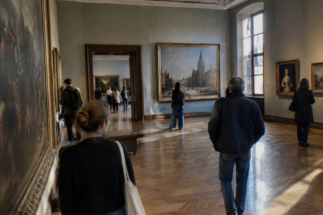 A spacious gallery hall inside the National Museum in Wroclaw with framed paintings on the walls