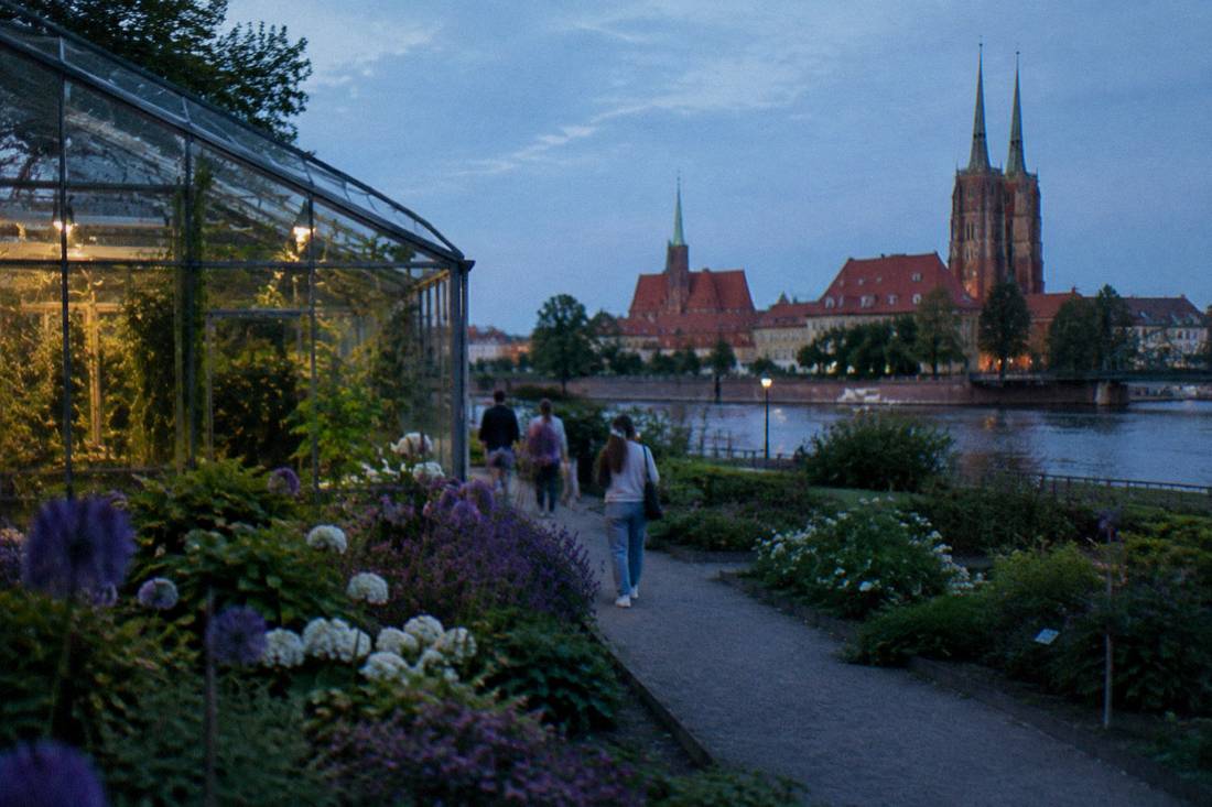 Flower beds and glasshouse at a riverside botanical garden in early summer