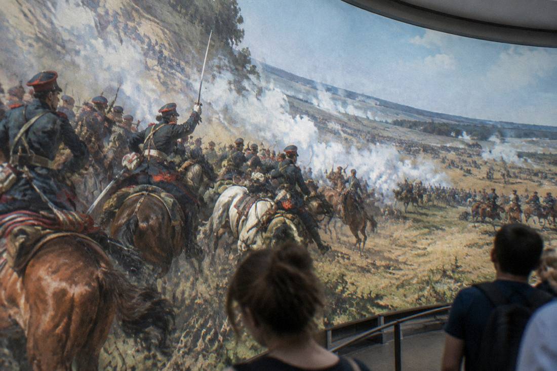 A close view of painted cavalrymen and smoke across the curved canvas surface
