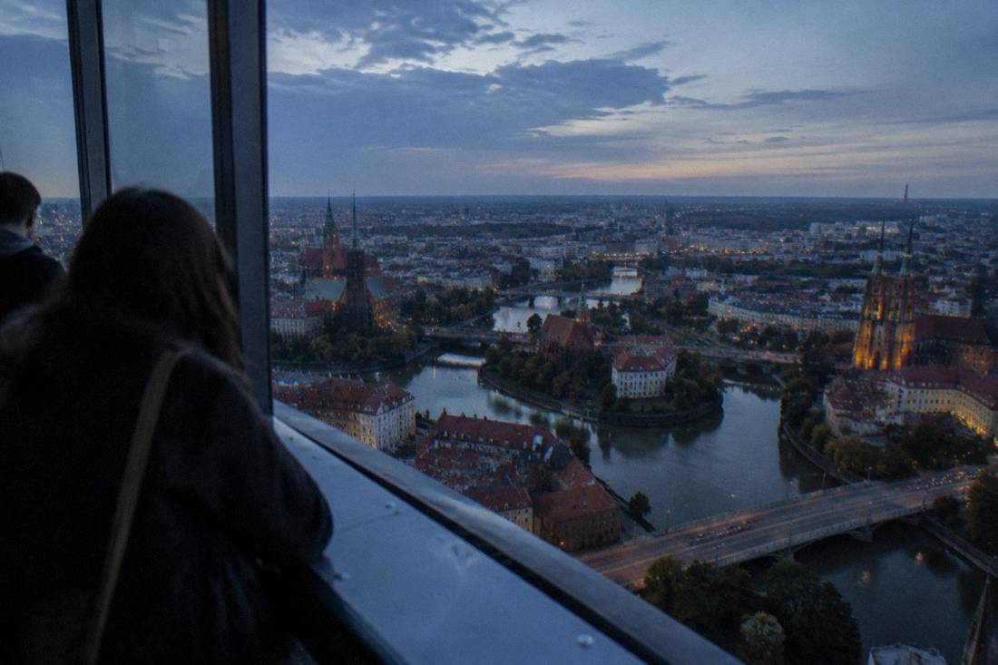 A wide rooftop panorama of church spires and river islands seen from high above the city