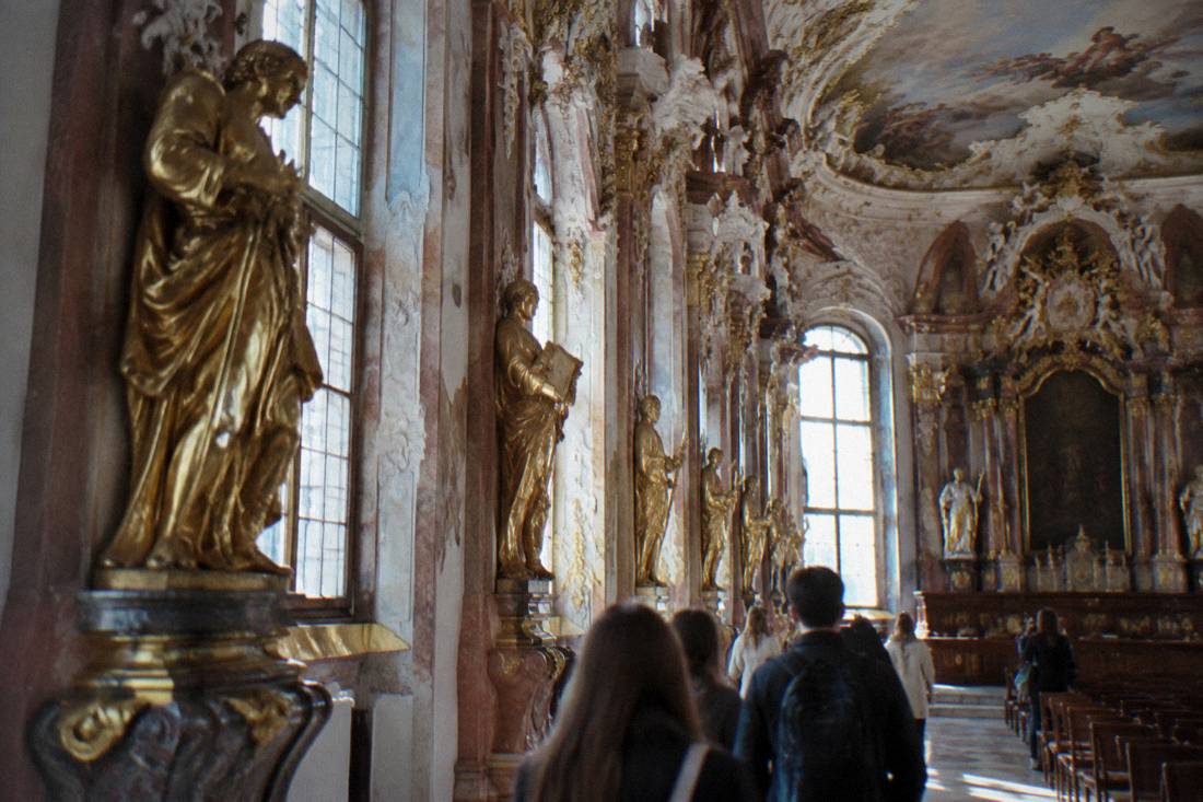 Gilded statues and ornate stucco decoration along the wall of a baroque hall