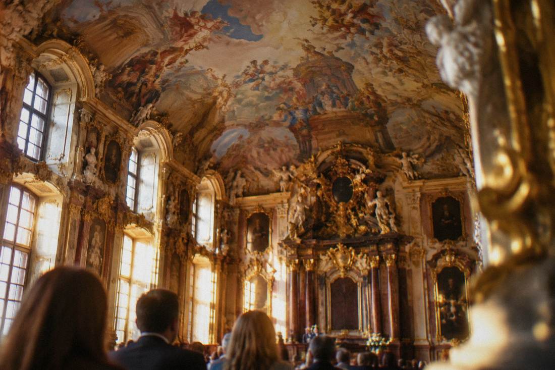 A painted ceiling with frescoes above the gilded interior of a ceremonial hall