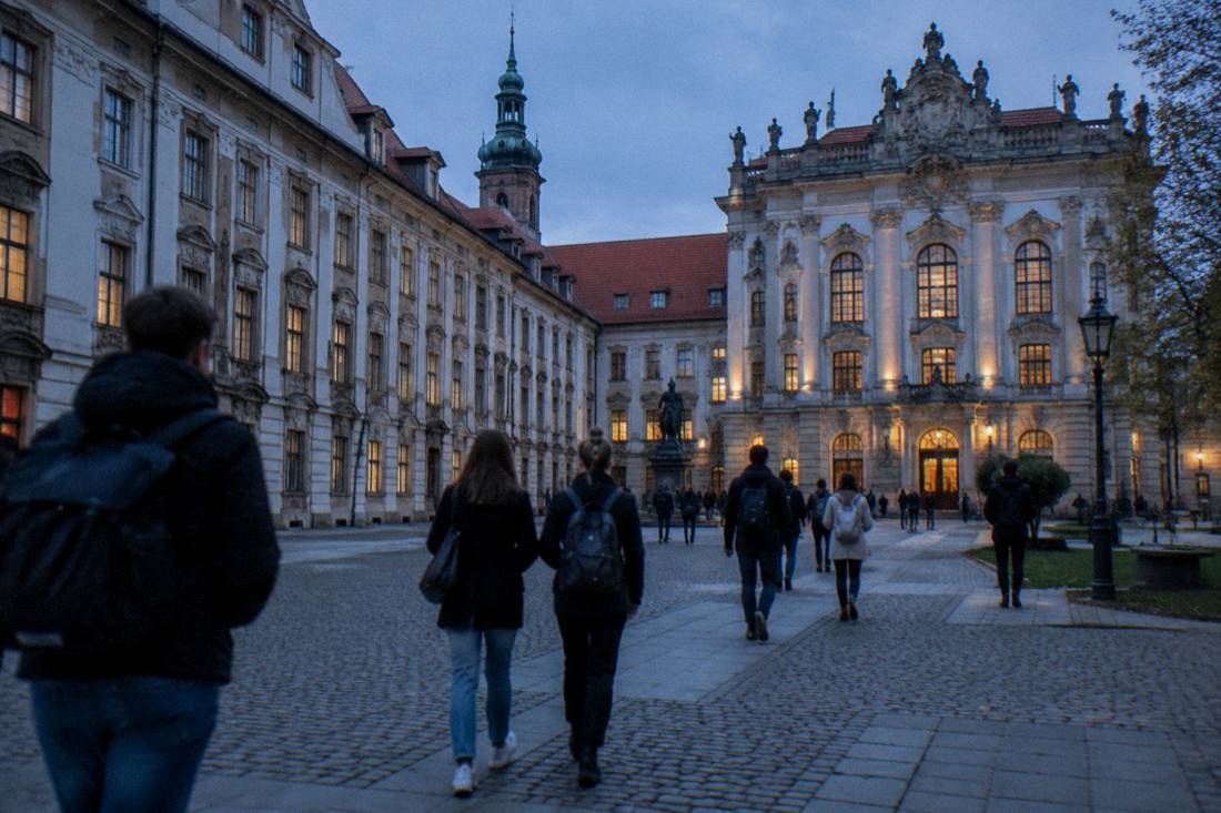 Students crossing a university courtyard between ornate historic buildings