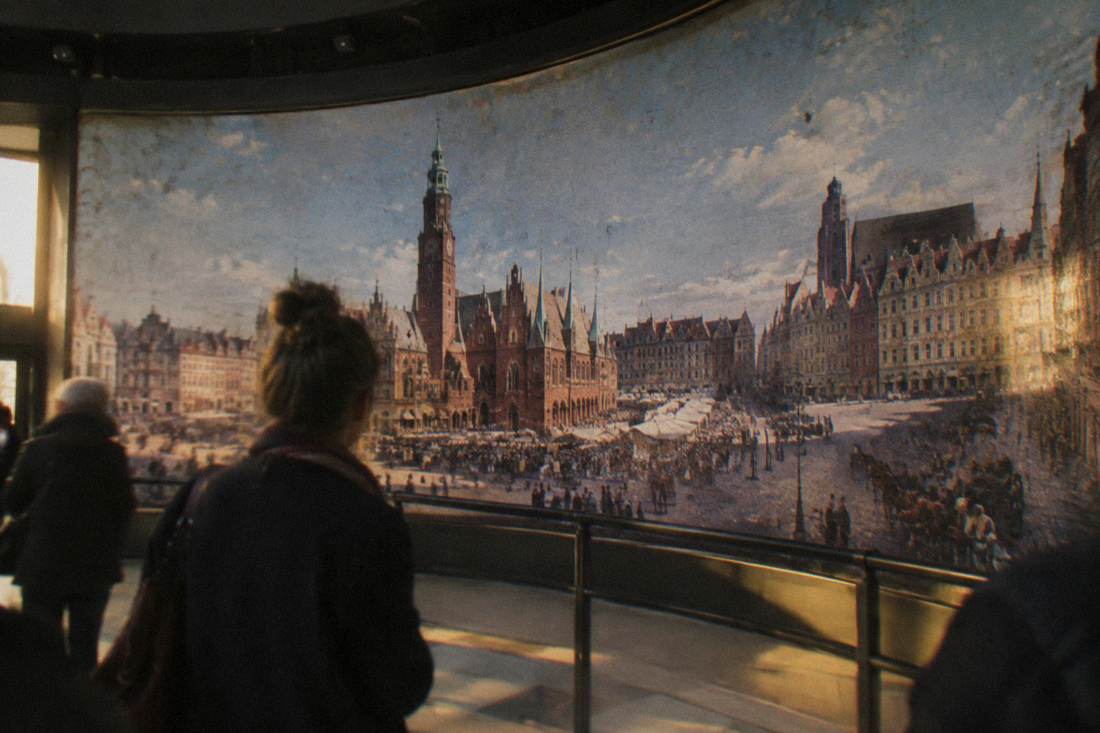 A visitor studying a large painted canvas panorama inside a rotunda museum