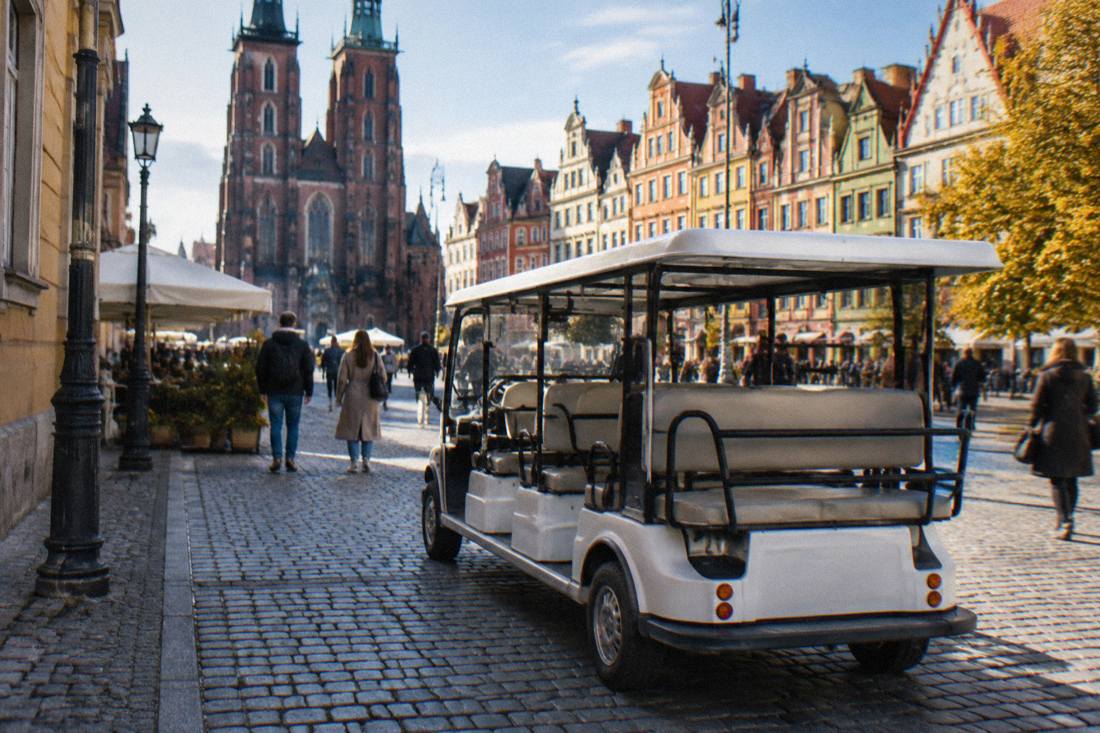 A small open electric sightseeing car parked on a cobbled street beside historic buildings