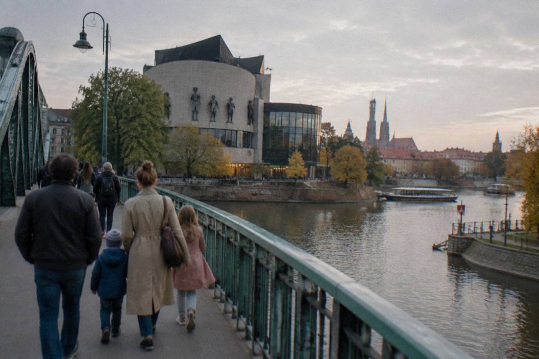 Families walking on a bridge between Wroclaw's Odra river islands in the late afternoon