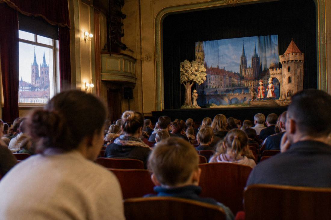 A warm theatre auditorium in Wroclaw with rows of seats filling before a family puppet performance