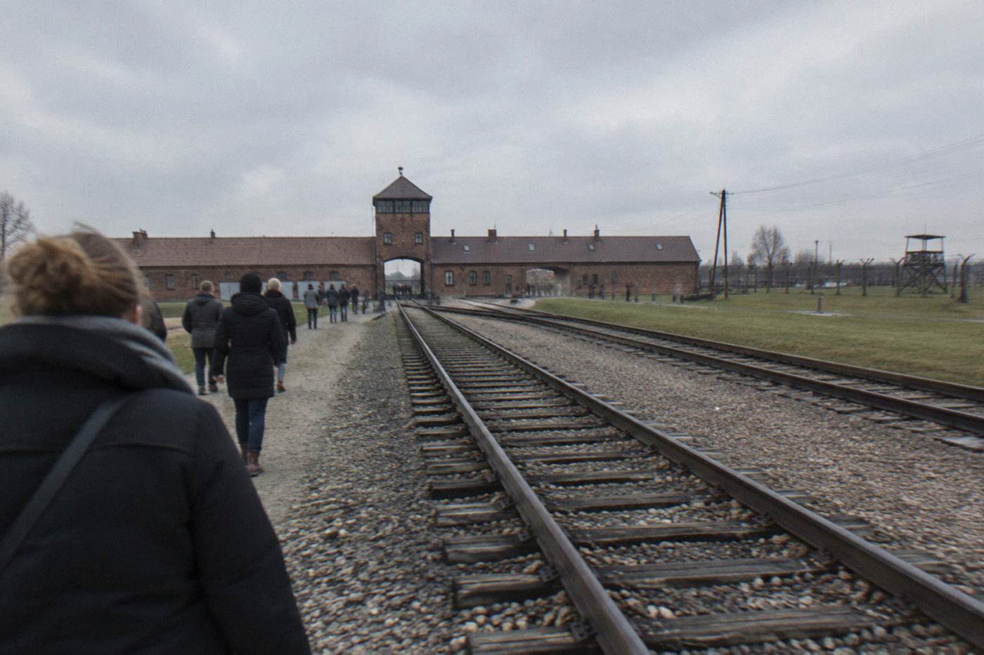 Railway tracks and a watchtower at the former Auschwitz-Birkenau memorial site under a grey sky