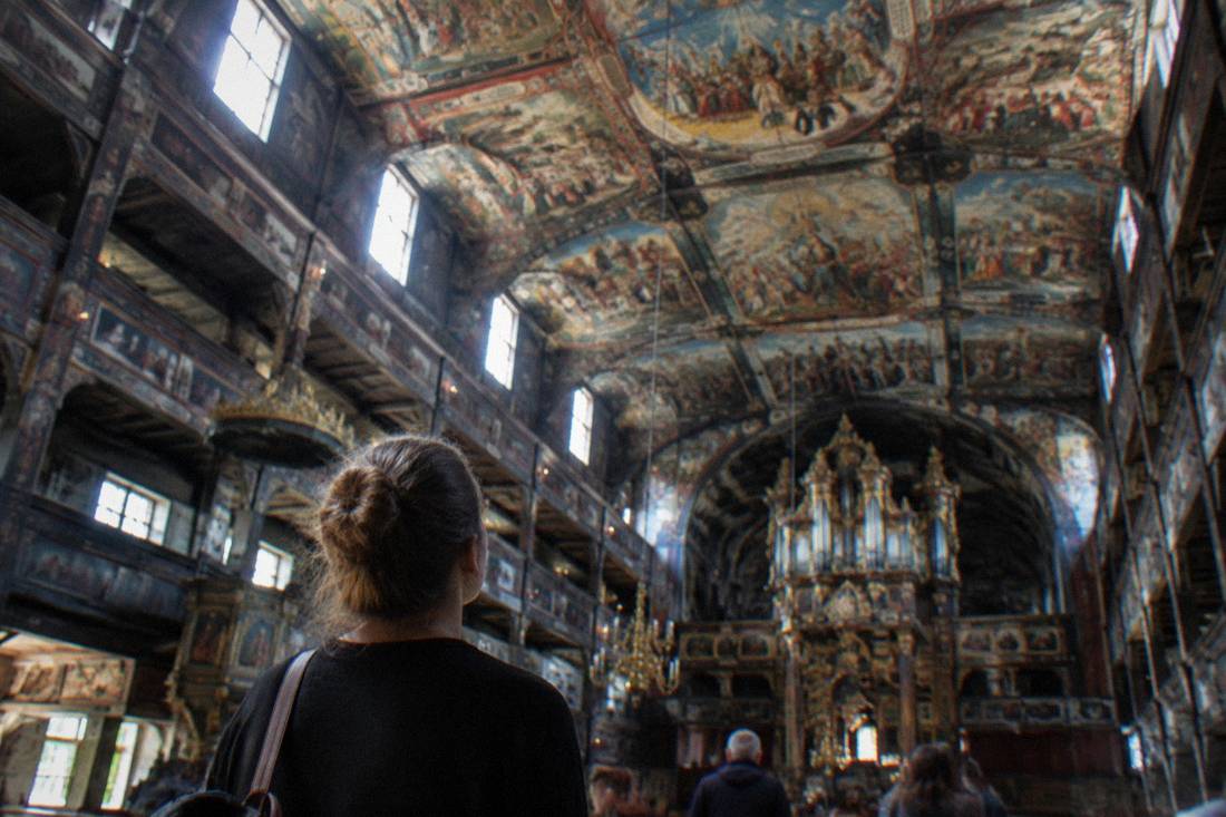 A visitor looking up at the high painted ceiling inside the Church of Peace in Swidnica