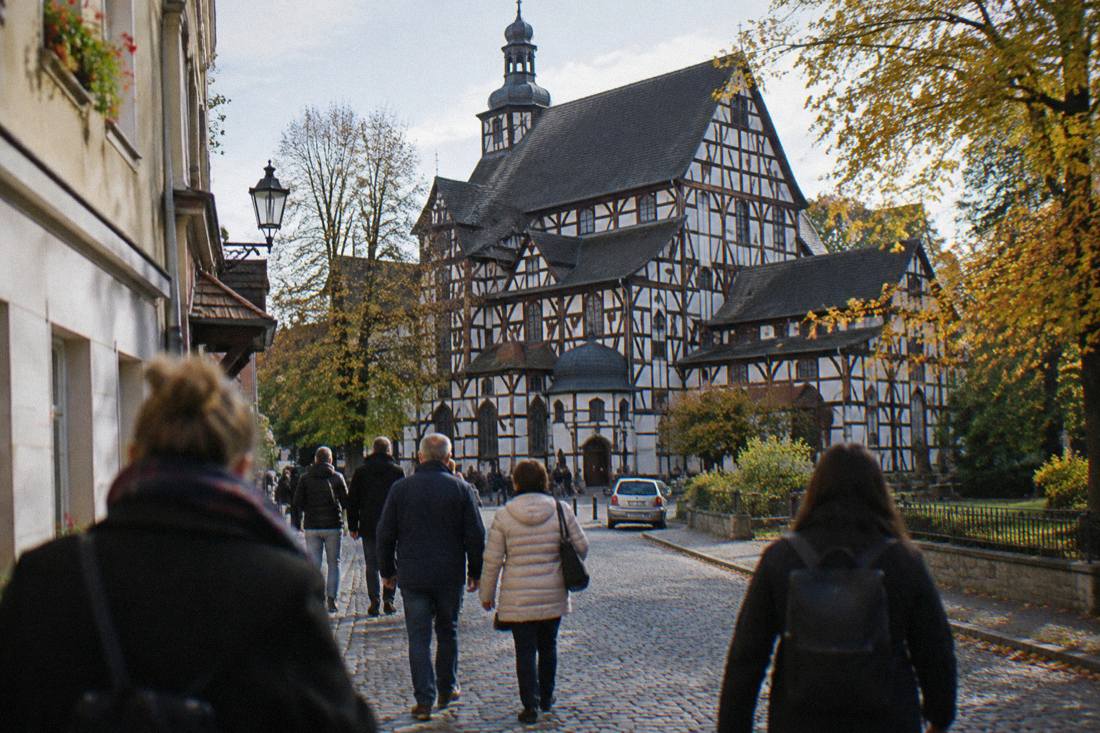 Tourists walking on a cobbled street in Swidnica toward the Church of Peace