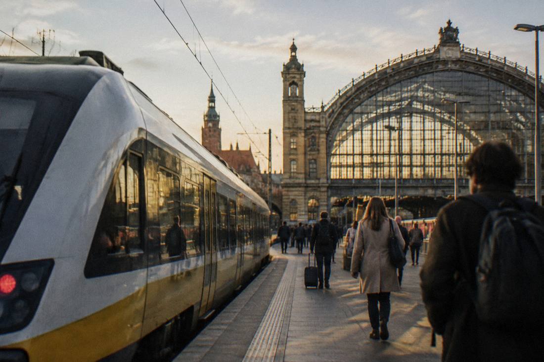 A modern train waiting at a platform beside a grand station hall