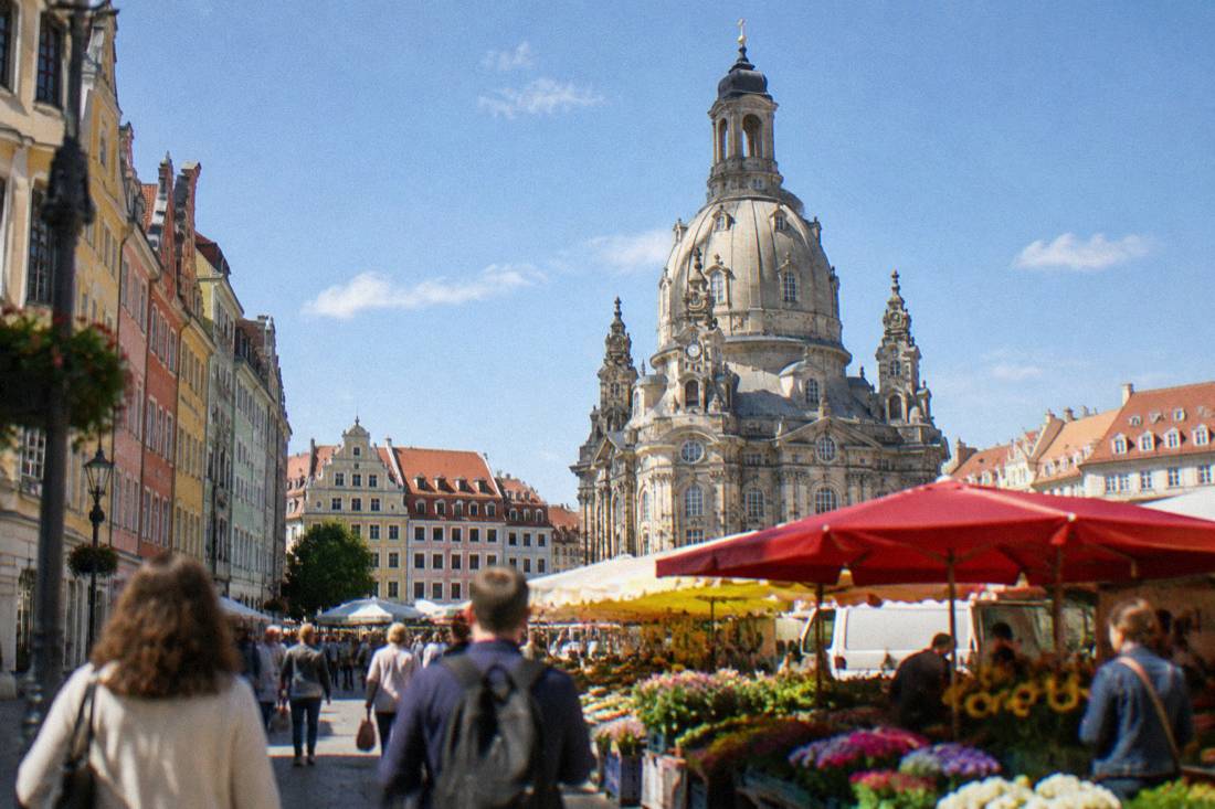 A large stone church dome towering over colorful market stalls