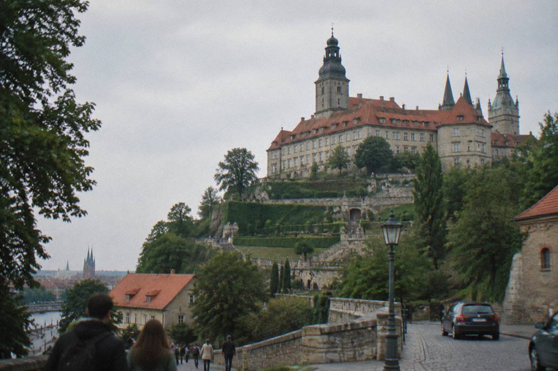 A hilltop castle with terraced gardens seen from below
