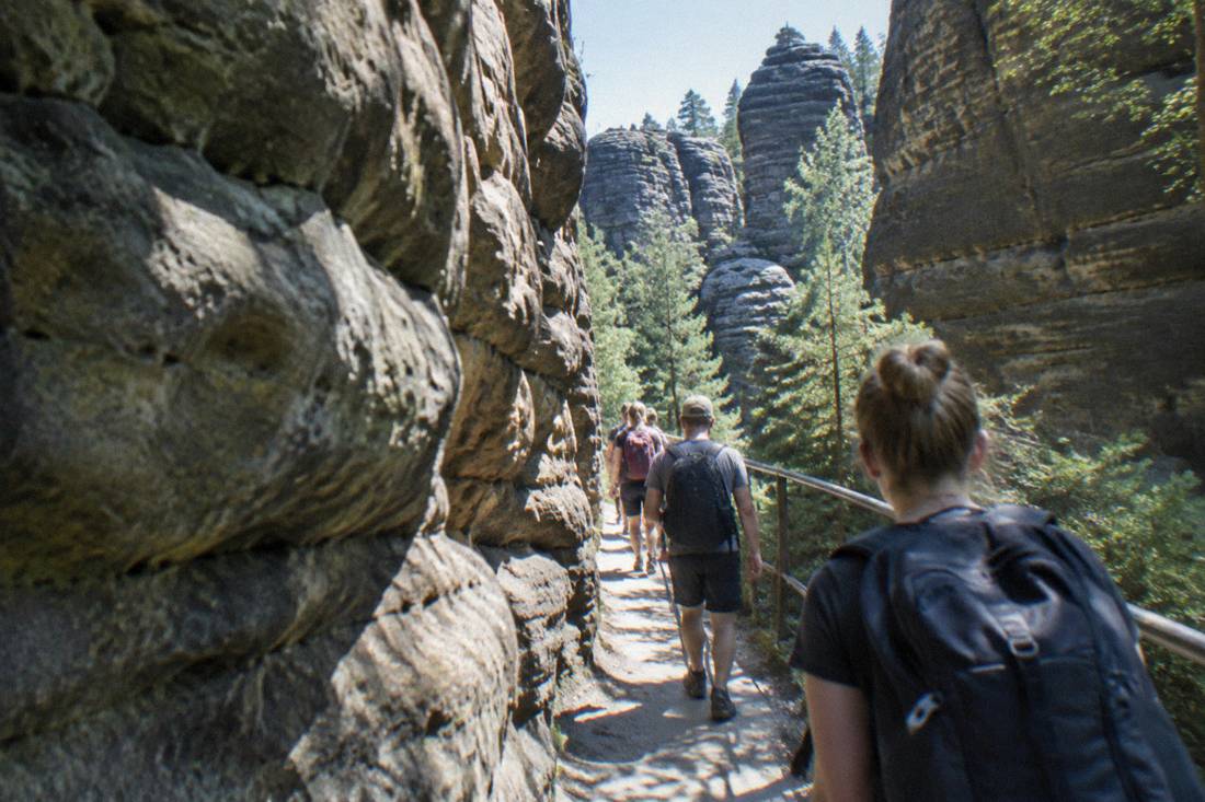Hikers walking a narrow passage between tall eroded sandstone walls