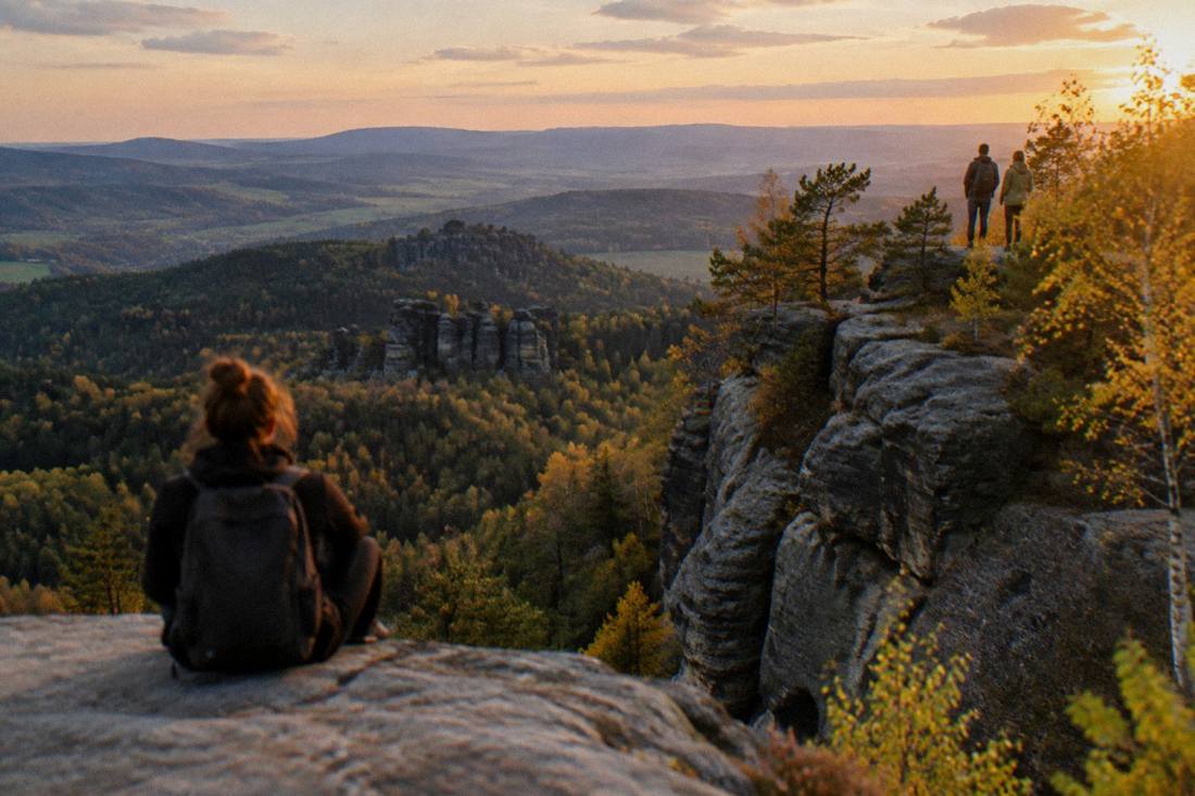 Evening light across a sandstone cliff edge with the Czech border hills beyond