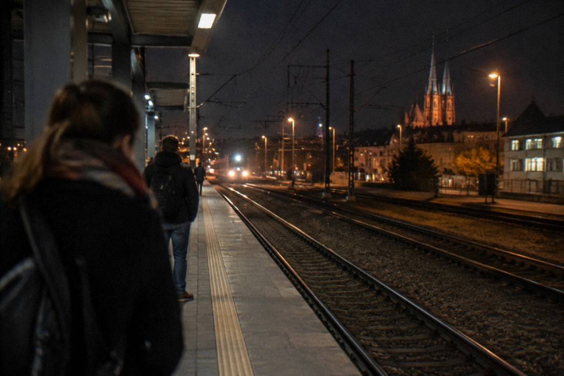 Railway platform at night with a train's lights visible down the track