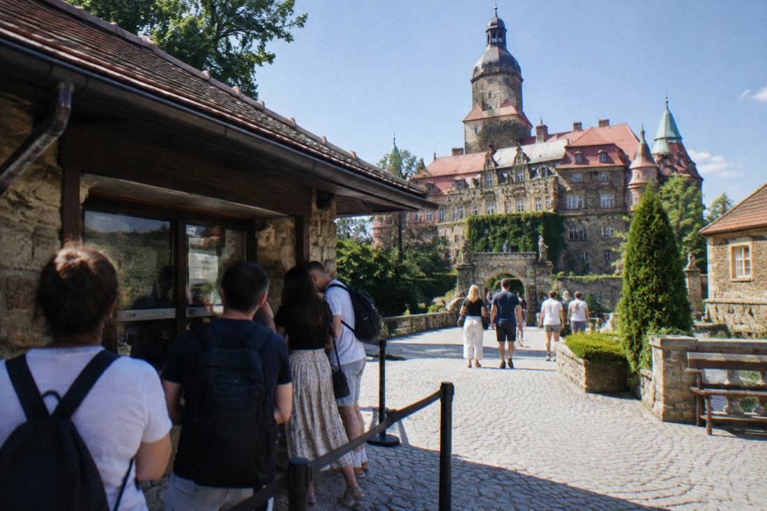 A ticket counter and visitors at the entrance courtyard of a large castle in Poland
