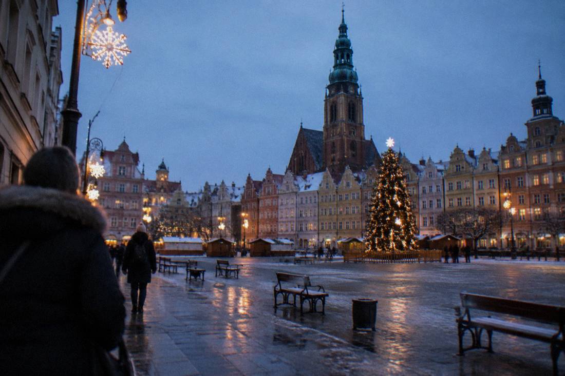 A market square in winter with festive lights and empty benches