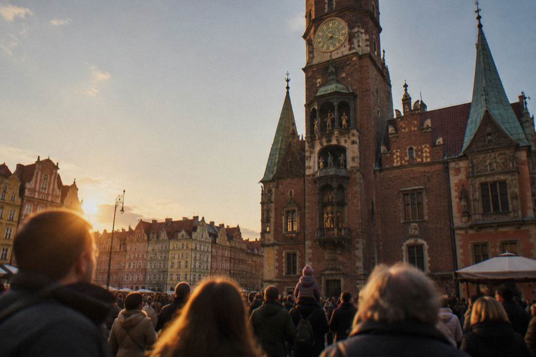 A crowd gathered below a Renaissance town hall tower waiting for the midday clock display