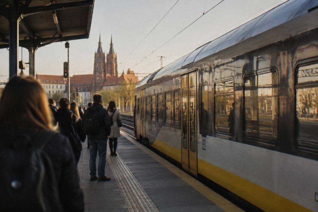 A regional train waiting at a platform in a Polish railway station in early morning light