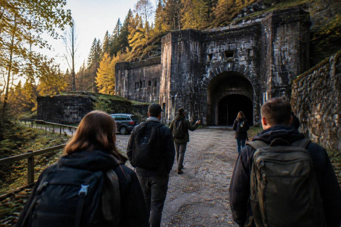 Small group of travelers walking with a guide toward a castle entrance in late afternoon
