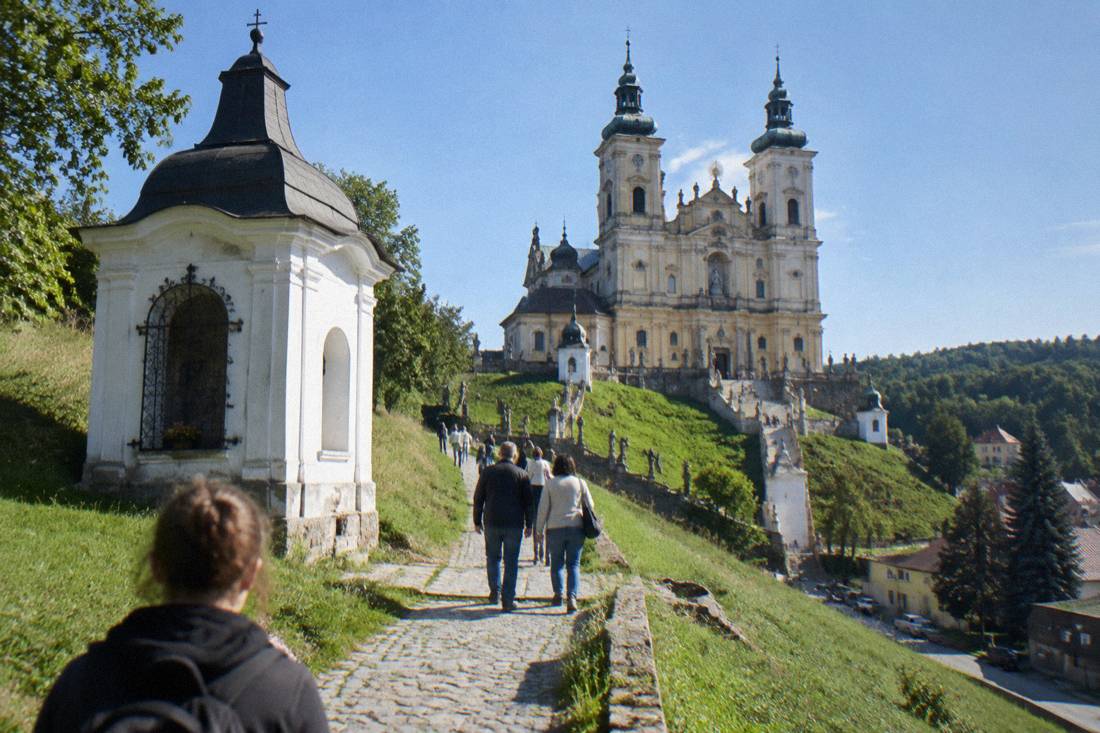 White chapel on a grassy hillside above the village, part of the Wambierzyce Calvary route