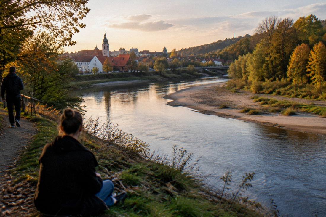 A river bend with sandy banks and forest at the edge of town under evening light