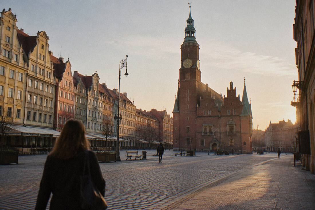 Wroclaw Market Square with few people, the Old Town Hall tower standing above empty cobblestones in early morning