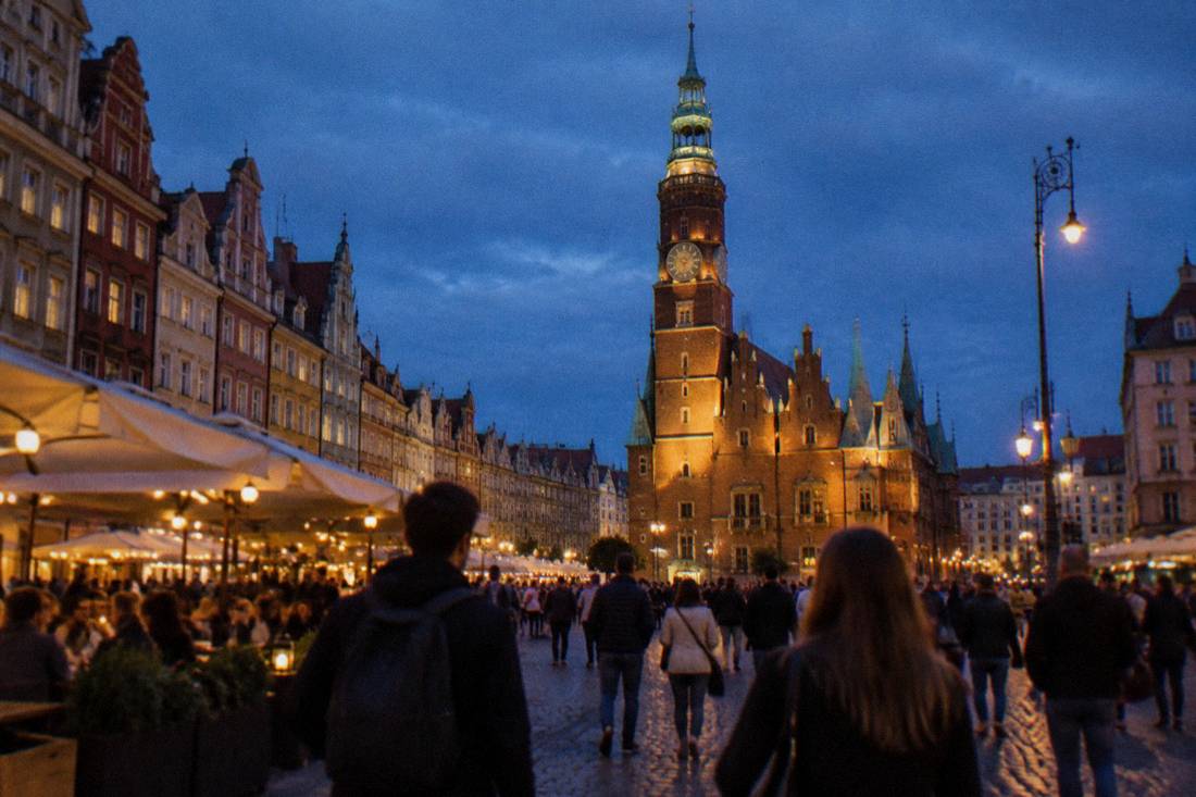 Wroclaw Market Square at night with illuminated facades and the Old Town Hall lit up above busy terraces