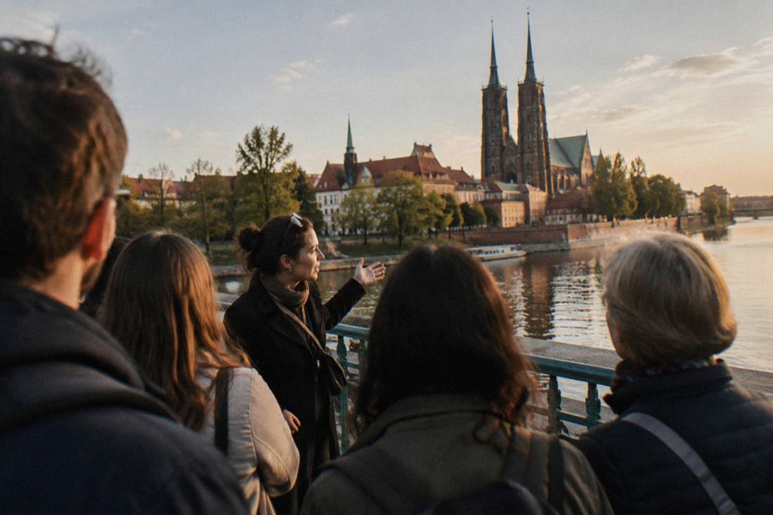 A guide speaking to a small group on a bridge over the Odra river toward Cathedral Island