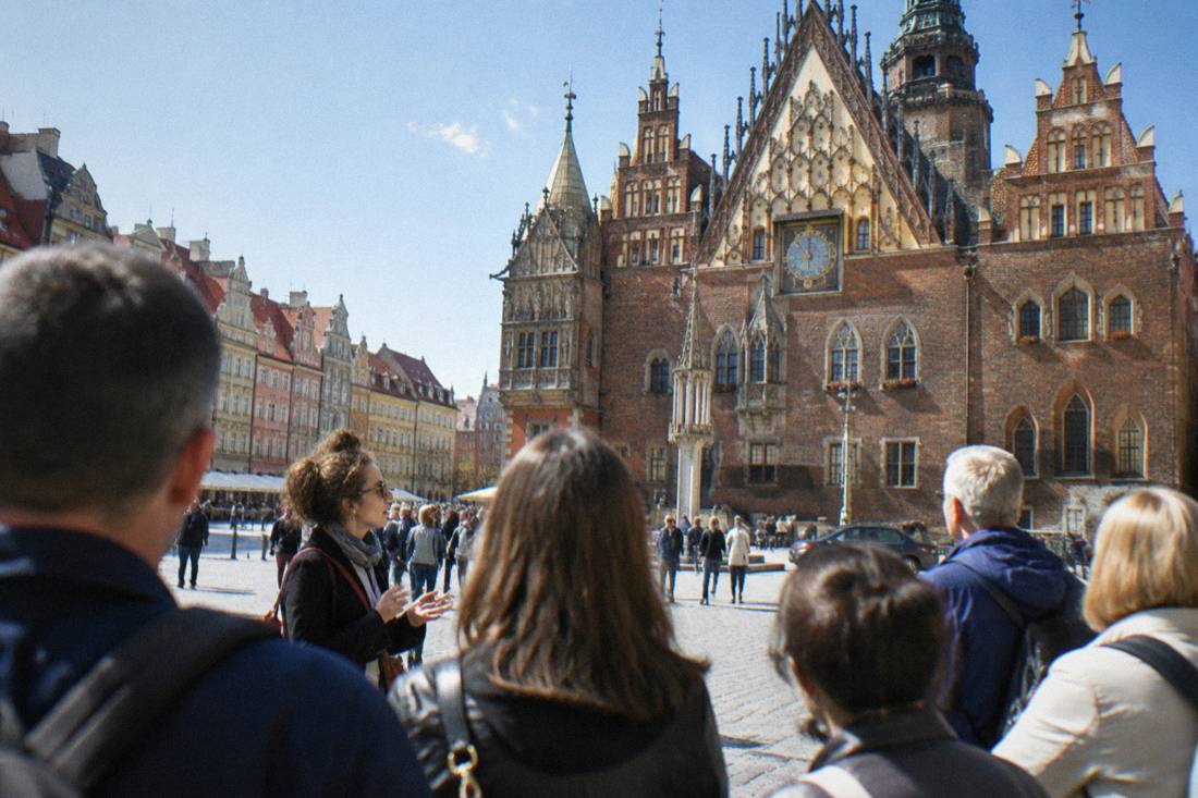 A tour group listening to a guide beside the Gothic Old Town Hall on Wroclaw's market square