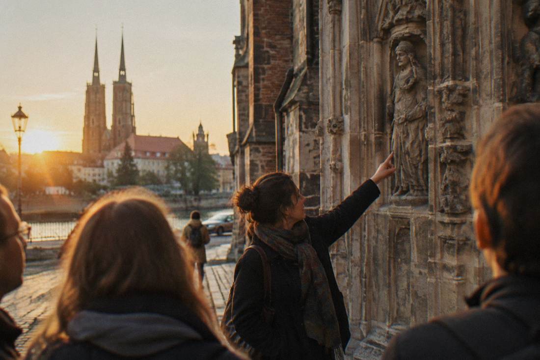 A guide pointing out carved details on a cathedral wall on Ostrow Tumski in Wroclaw