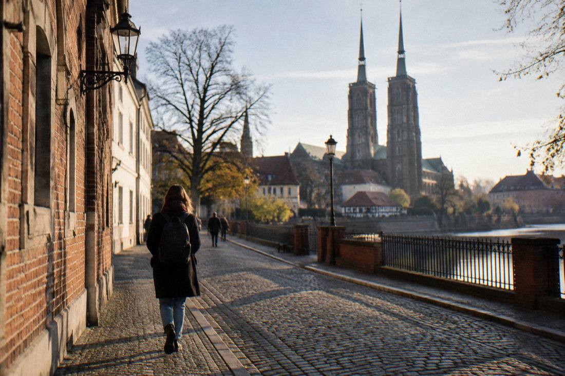 A traveler walking alone down a cobblestone lane on Cathedral Island in Wroclaw