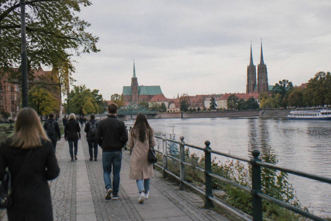 People strolling along a riverside promenade on one of Wroclaw's Odra islands