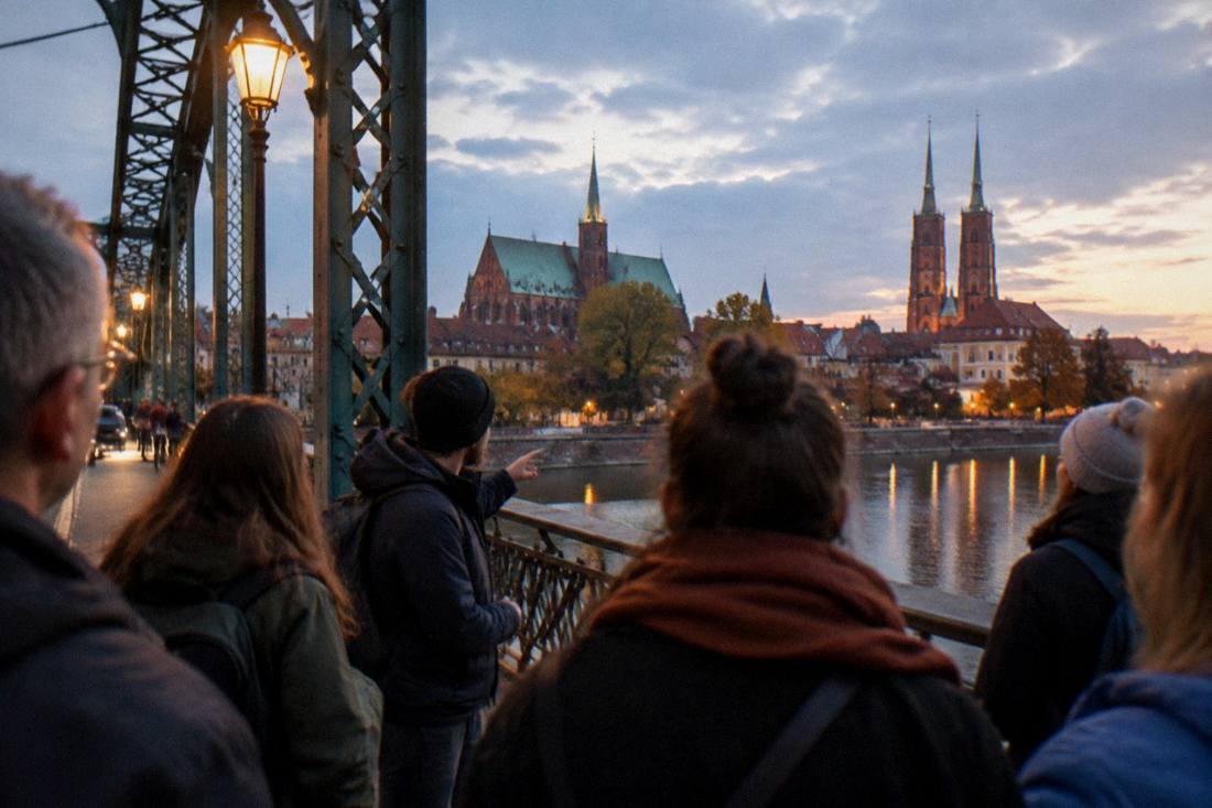 A walking tour group pausing on a floodlit bridge in Wroclaw in the early evening